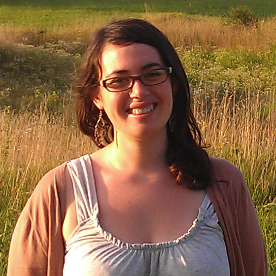 Adriane Garnreiter, Environmental Scientist and Communications Specialist, stands in business casual attire with a grassy field as background.