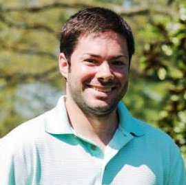 Taylor Fontaine, Environmental Scientist, stands in business casual attire in front of a sunlit leafy green background.