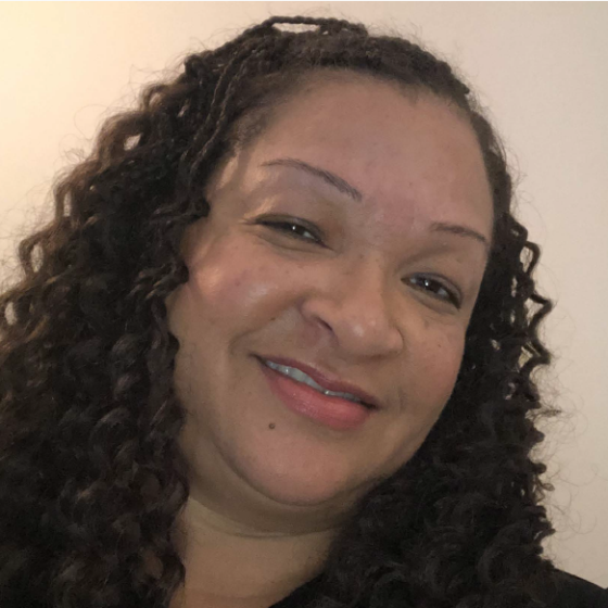 Deniece Brooks, Corporate Controller and Human Resources Manager, stands smiling in front of a light-colored background.