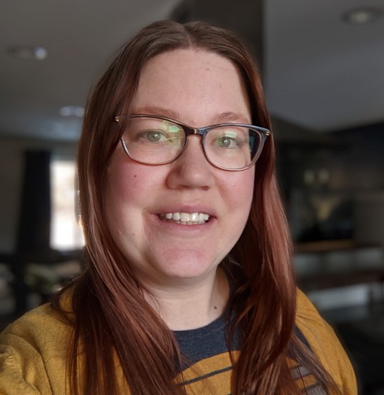 Mindi Lundberg, Ecologist, stands inside in business casual attire.