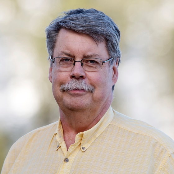 Bob Brobst, Senior Environmental Engineer, stands in business casual attire in front of a natural background.