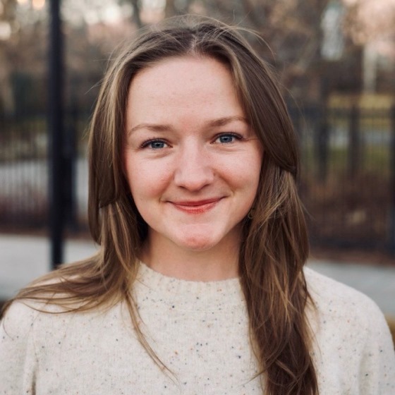 Kenna Morgan, Environmental Scientist, stands outside wearing business casual attire in front of an urban park.